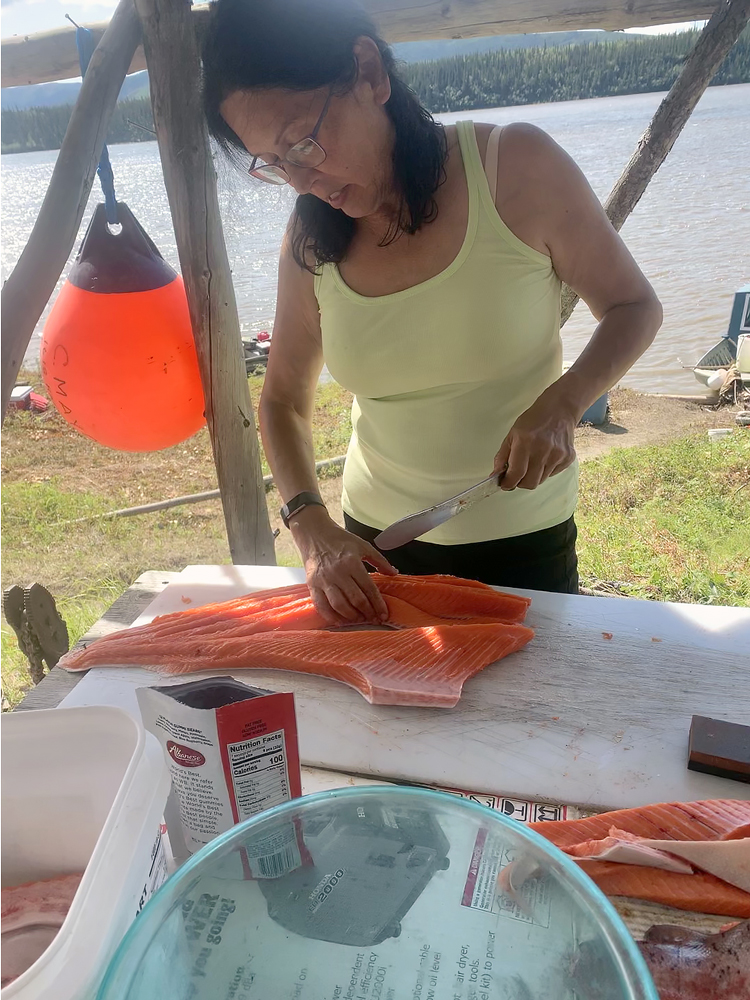 Kathy cleaning salmon by the river